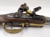 un vieux pistolet avec une crosse en laiton sur un fond blanc