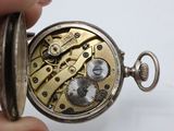 someone is holding a pocket watch in their hand on a white surface