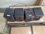 four speakers sitting on a wooden table with wires