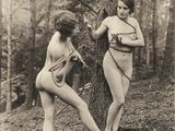 une vieille photo montrant deux femmes debout près d'un arbre dans les bois