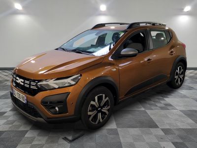 Une voiture marron est garée dans une pièce au sol à carreaux.