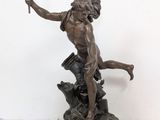 bronze statue of a man holding a torch in one hand and a bird in the other