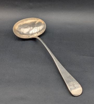 cuillère en argent avec un long manche, posée sur une surface noire