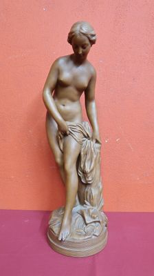 a bronze statue of a woman sitting on a rock