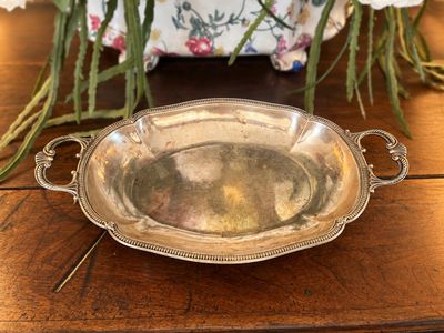 une assiette en argent posée sur une table en bois, avec des fleurs en arrière-plan