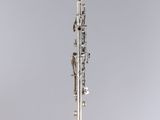 a silver and black clarinet sitting on top of a white pedestal