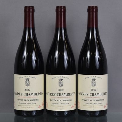 three bottles of red wine are lined up on a glass table