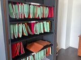 une bibliothèque sur laquelle sont posés de nombreux dossiers, dans une pièce