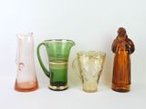 several different colored glass vases are lined up on a white surface
