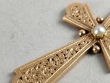 a gold cross with a pearl in it on a table