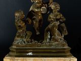 bronze statue of three children playing with a bird on a marble base