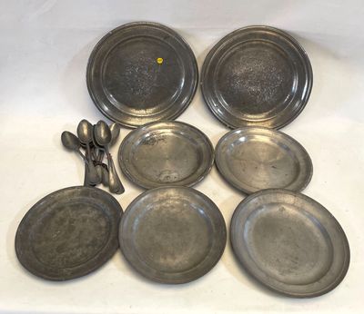 plusieurs assiettes et cuillères en argent posées sur un fond blanc orné d'un point jaune