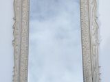 an old mirror hanging on a wall with a sky in the background