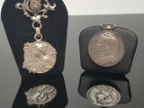 deux pièces d'argent et un collier exposés sur un fond noir