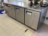 un grand plan de travail en inox dans une cuisine, sur lequel sont posées des casseroles et des poêles