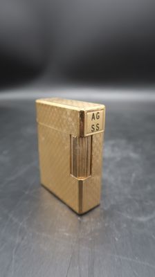 a gold lighter sitting on a table with a black background