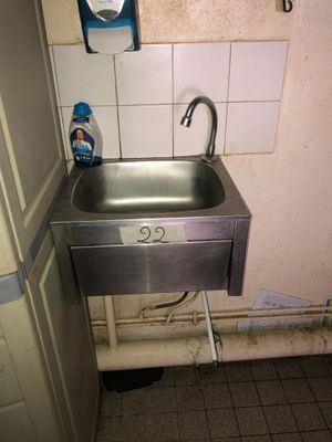 a sink in the corner of a bathroom with a faucet and soap dispenser on the wall