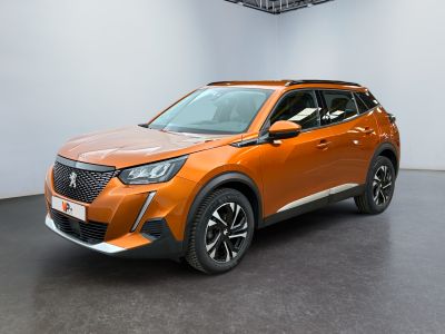 Le SUV orange est garé dans une grande pièce au sol noir.