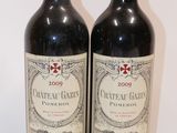 two bottles of red wine sitting next to each other on a table