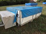 a blue tarp covering a white trailer in the grass