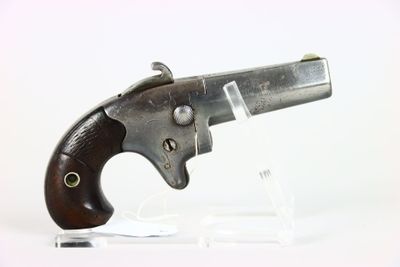 un vieux pistolet avec une crosse en bois, posé sur un socle transparent