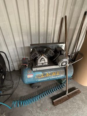 a blue air compressor sitting next to a pile of tools
