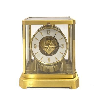 une horloge en or posée sur une surface blanche