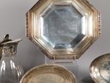 a lot of silver plates and silver vases on a table