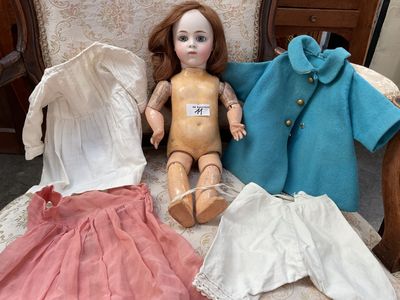 une poupée assise sur une chaise, habillée