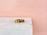 une bague en or sertie de pierres noires et blanches, posée sur un bloc de marbre