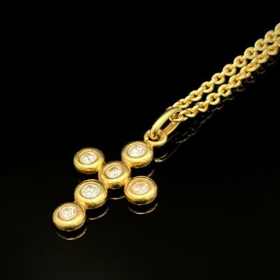 une image représentant un pendentif en forme de croix en or suspendu à une chaîne