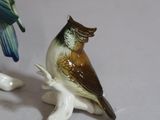 two figurines of birds that are sitting on a branch