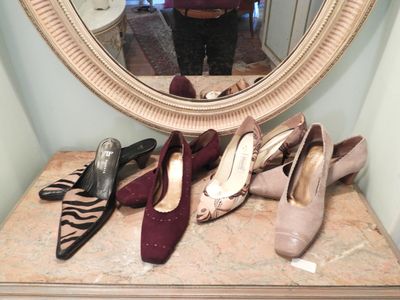a woman taking a selfie in front of a mirror with several pairs of shoes on a table