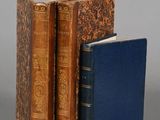 three books are stacked on top of each other on a gray surface