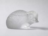 une figurine en verre représentant un éléphant posée sur une surface blanche