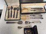 une boîte à couverts posée sur une table, contenant un couteau, une fourchette et des cuillères