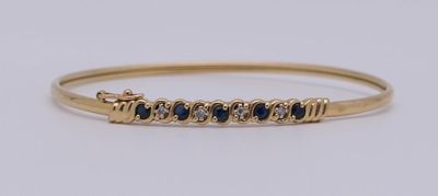 un bracelet rigide en or jaune serti de saphirs bleus
