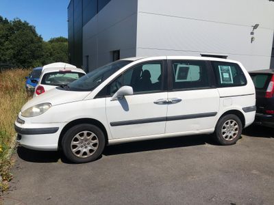 une petite camionnette blanche garée devant un bâtiment