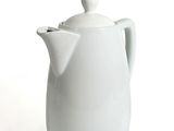 a white coffee pot with a lid on a white table