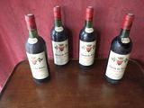 four bottles of wine are lined up on a wooden table