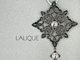 une photo en noir et blanc représentant une croix à laquelle est suspendue une perle