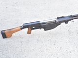 an old machine gun with a wooden handle on a concrete surface