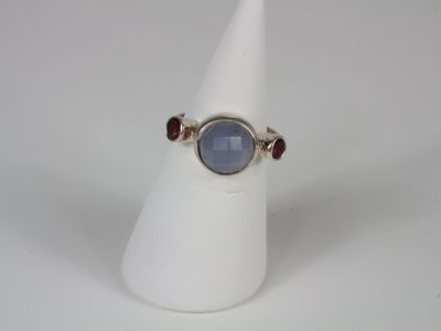 a close up of a ring on a white cone with a blue stone
