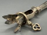 une cuillère en argent avec un manche en métal et une paire de ciseaux