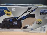packaging of a blue and black lawn mower sitting on top of a wooden table