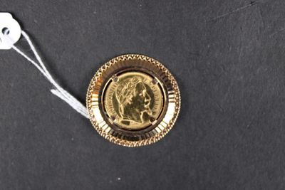 une pièce d'or sur laquelle est représenté un visage, posée sur une surface noire
