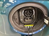 a close up of a blue car with an electric charger plugged into it
