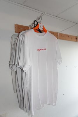 un t-shirt blanc suspendu à un cintre en bois dans une pièce