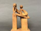 wooden sculpture of a man and woman sitting on a bench