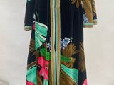 a black and green dress with pink flowers on a mannequin